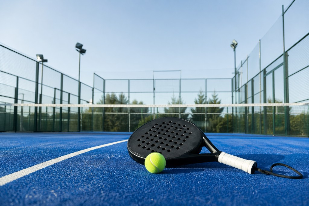 Dynamic action shot of a tennis player mid-serve on a professional blue hardcourt with bright sunlight and cinematic motion blur
